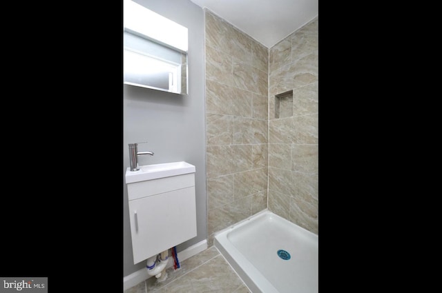 bathroom with a tile shower, tile patterned flooring, and vanity