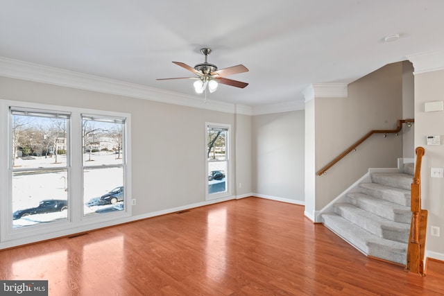 empty room with ceiling fan, crown molding, and a wealth of natural light