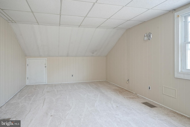 bonus room featuring light carpet, lofted ceiling, and wooden walls