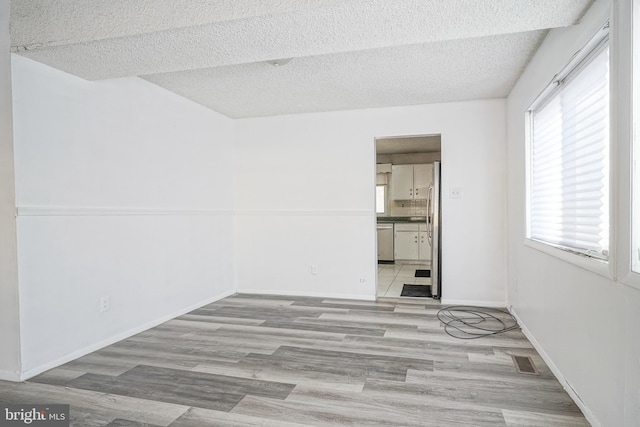 empty room with a textured ceiling and light wood-type flooring