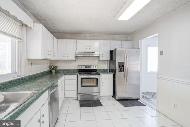 kitchen with white cabinetry, a textured ceiling, stainless steel appliances, and light tile patterned flooring