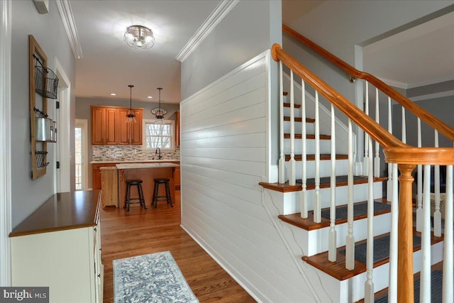 staircase with hardwood / wood-style floors, crown molding, and sink