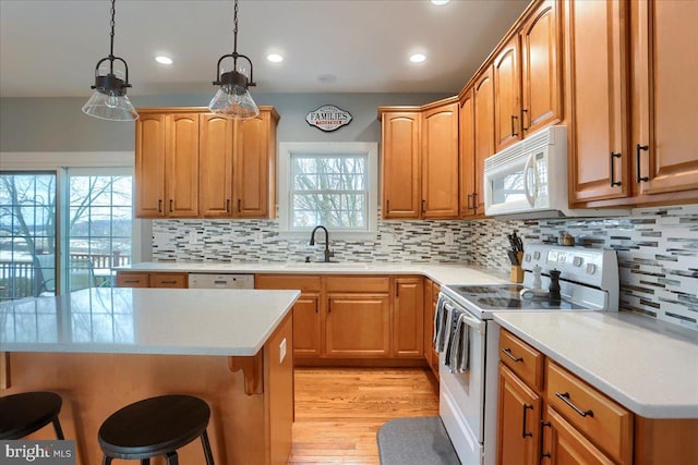 kitchen featuring sink, tasteful backsplash, decorative light fixtures, white appliances, and a breakfast bar