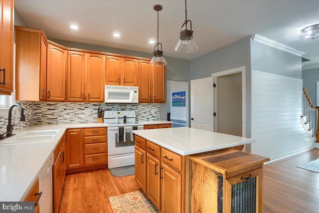 kitchen featuring a center island, sink, tasteful backsplash, decorative light fixtures, and white appliances