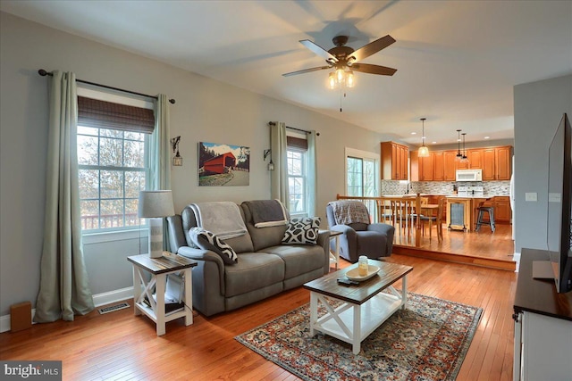 living room with ceiling fan and light hardwood / wood-style flooring