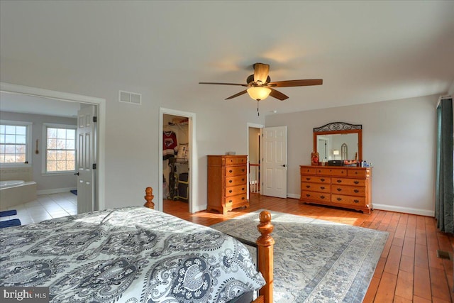 bedroom featuring a walk in closet, ensuite bathroom, ceiling fan, light hardwood / wood-style floors, and a closet