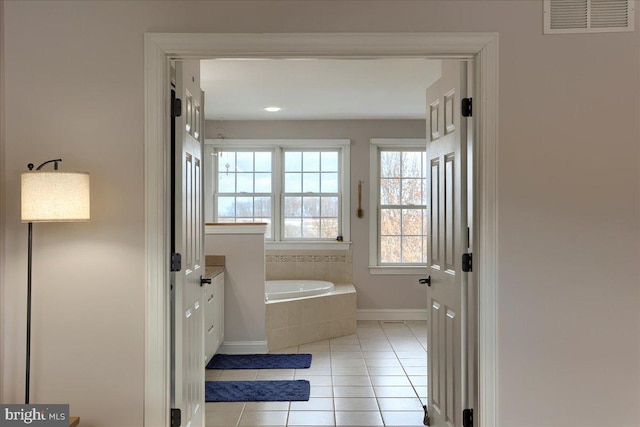 bathroom with tile patterned flooring, vanity, and tiled tub