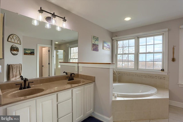 bathroom with tile patterned floors, tiled tub, a wealth of natural light, and vanity