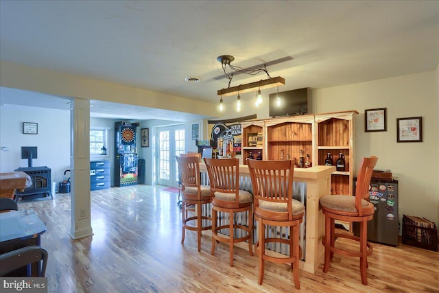 dining area with light hardwood / wood-style floors, a wood stove, and french doors