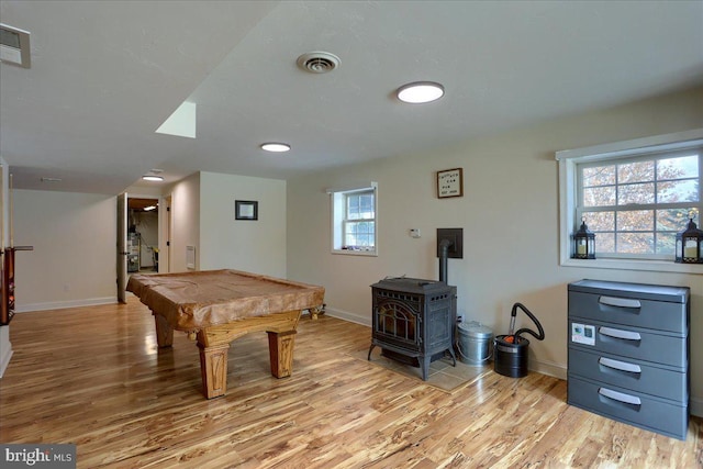 recreation room featuring a wood stove, a wealth of natural light, light wood-type flooring, and billiards