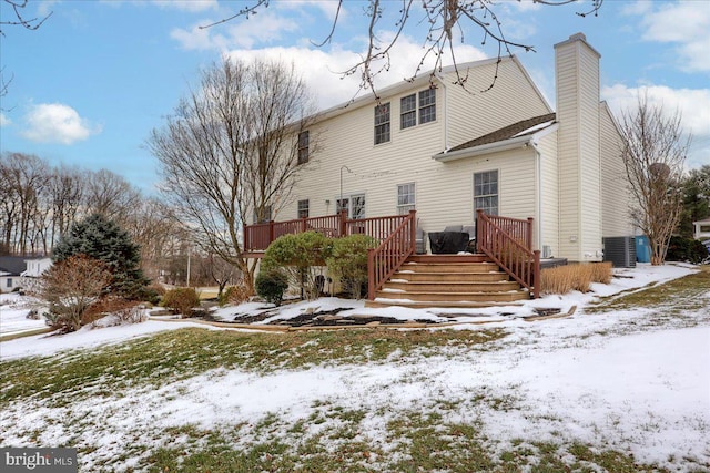 snow covered back of property featuring a wooden deck and central AC unit