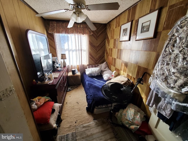 bedroom featuring carpet, a textured ceiling, ceiling fan, and wooden walls