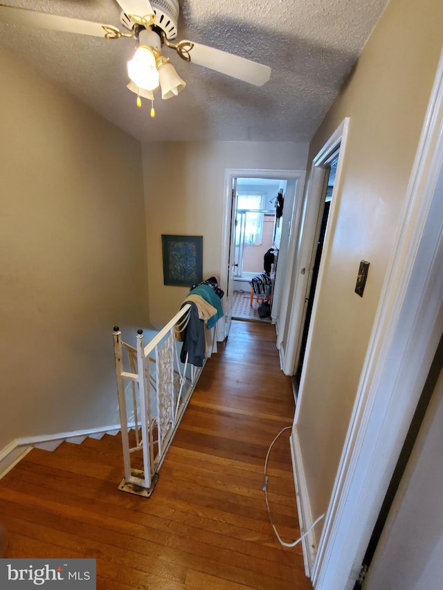 corridor with dark hardwood / wood-style flooring and a textured ceiling