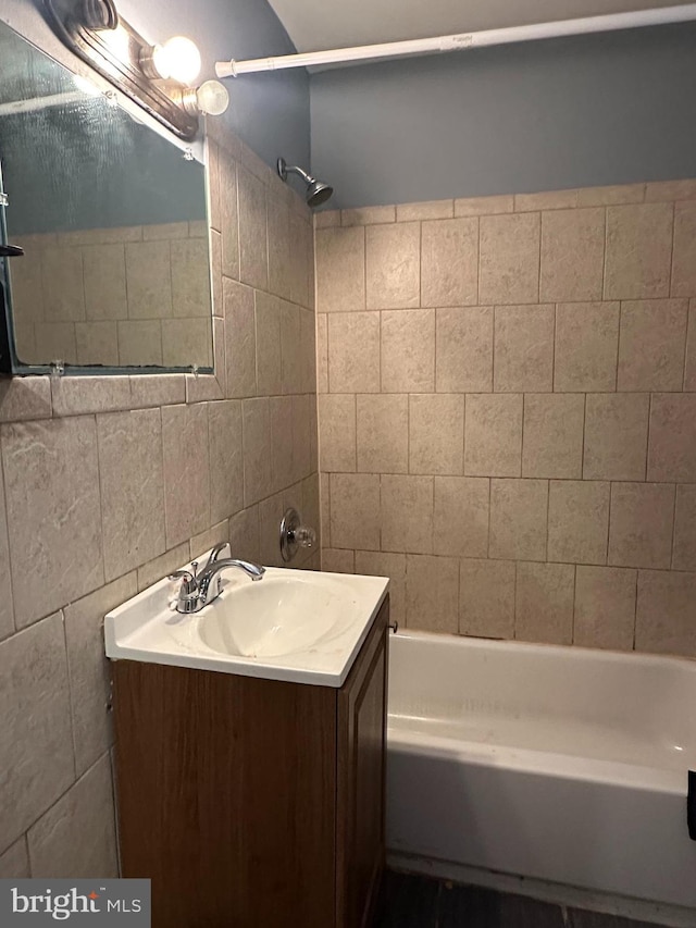 bathroom with vanity, decorative backsplash, tile walls, and tiled shower / bath