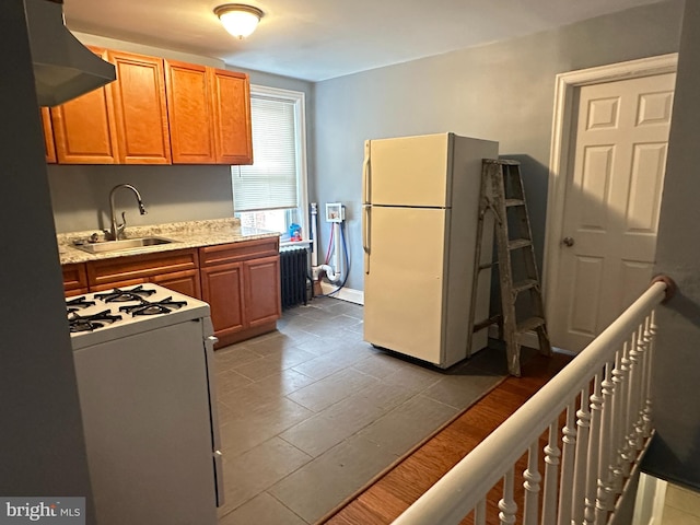 kitchen with sink, radiator heating unit, light hardwood / wood-style flooring, extractor fan, and white appliances