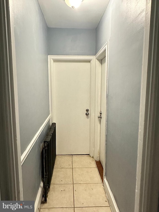 hall with radiator heating unit and light tile patterned floors