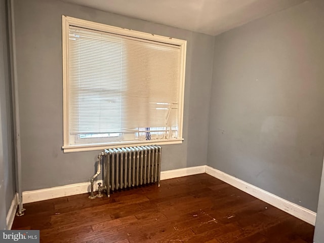 unfurnished room with dark hardwood / wood-style floors and radiator