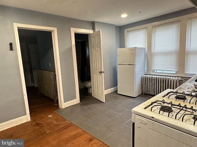 kitchen with white refrigerator, dark hardwood / wood-style flooring, radiator, and gas stove