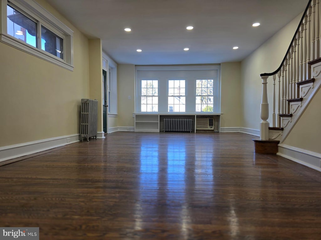 unfurnished living room featuring radiator heating unit and dark wood-type flooring