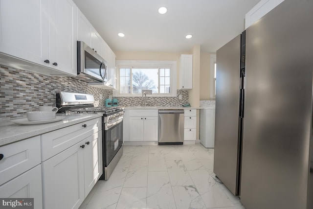 kitchen featuring backsplash, sink, white cabinets, and stainless steel appliances