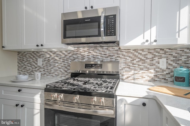 kitchen featuring white cabinets, decorative backsplash, light stone countertops, and appliances with stainless steel finishes