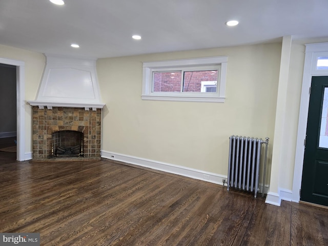 unfurnished living room featuring dark hardwood / wood-style flooring, radiator heating unit, and a tile fireplace