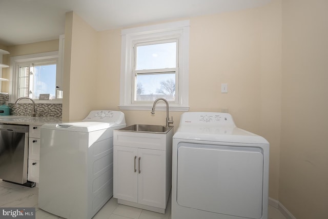 clothes washing area with cabinets, washer and clothes dryer, and sink