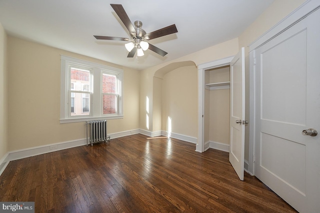 unfurnished bedroom featuring radiator heating unit, dark hardwood / wood-style flooring, a closet, and ceiling fan