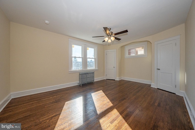 empty room with radiator heating unit, ceiling fan, and dark wood-type flooring