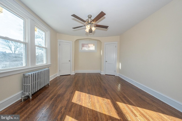 empty room with radiator heating unit, ceiling fan, and dark wood-type flooring