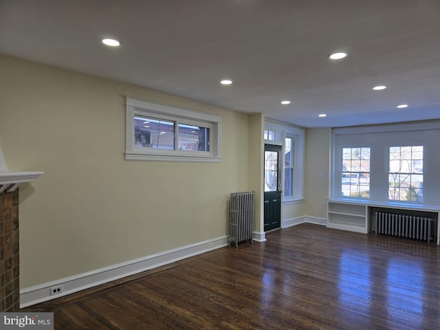 interior space featuring dark hardwood / wood-style floors, a brick fireplace, and radiator