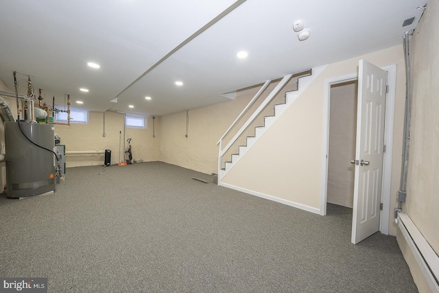 basement featuring baseboard heating, water heater, and carpet floors