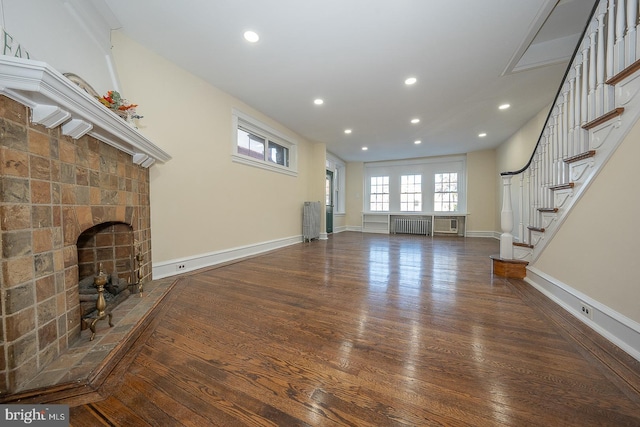 unfurnished living room featuring dark hardwood / wood-style flooring, radiator heating unit, and a fireplace