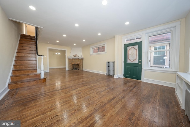 foyer entrance featuring wood-type flooring and a brick fireplace