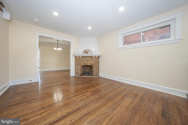 unfurnished living room with a notable chandelier, wood-type flooring, and a fireplace