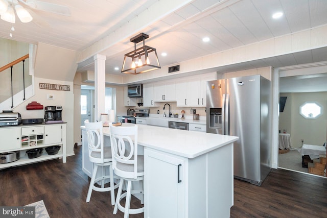 kitchen featuring white cabinetry, stainless steel appliances, dark hardwood / wood-style floors, pendant lighting, and a kitchen island