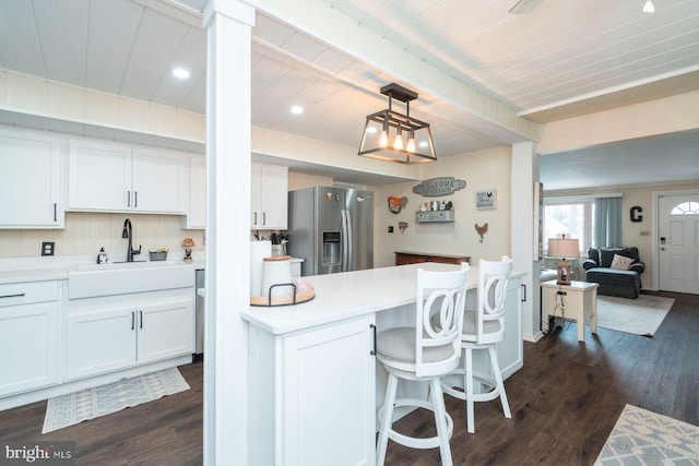 kitchen featuring white cabinets, stainless steel refrigerator with ice dispenser, hanging light fixtures, and sink