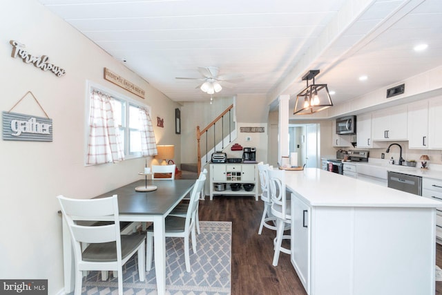 kitchen featuring pendant lighting, white cabinets, appliances with stainless steel finishes, a kitchen island, and dark hardwood / wood-style flooring