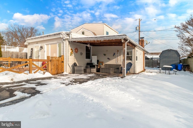 snow covered back of property featuring a shed