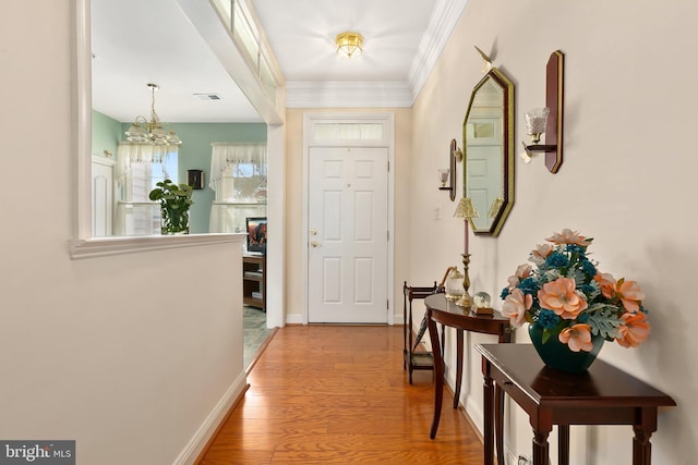 interior space featuring a notable chandelier, light hardwood / wood-style floors, and crown molding