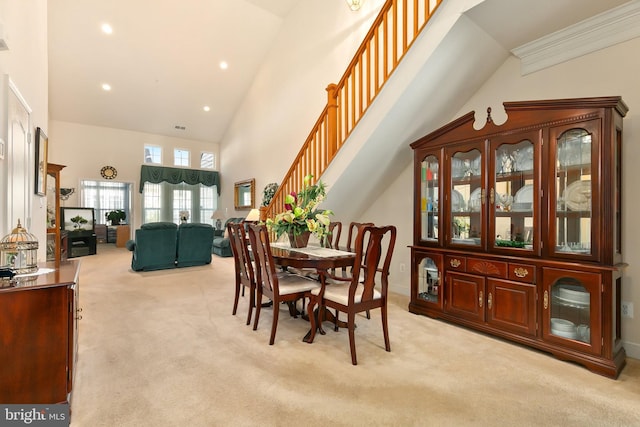 dining area with light carpet, a high ceiling, and crown molding