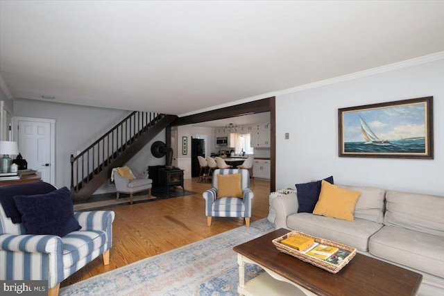 living room featuring wood-type flooring, a wood stove, and crown molding