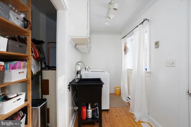 washroom with electric water heater, rail lighting, ornamental molding, light hardwood / wood-style floors, and washer / dryer