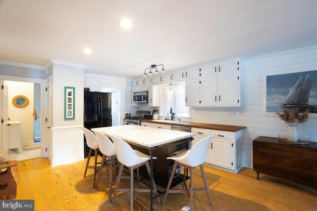 dining space featuring crown molding, sink, track lighting, and light wood-type flooring