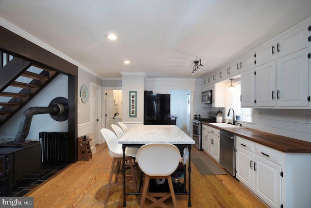 kitchen featuring white cabinetry, a center island, sink, a kitchen bar, and appliances with stainless steel finishes