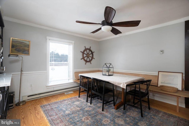 dining area featuring ceiling fan, dark hardwood / wood-style flooring, crown molding, and a baseboard heating unit