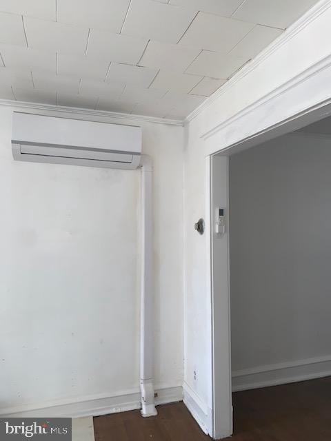 unfurnished room featuring a wall mounted air conditioner, dark hardwood / wood-style flooring, and crown molding