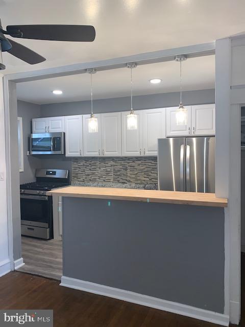 kitchen with pendant lighting, ceiling fan, tasteful backsplash, white cabinetry, and stainless steel appliances