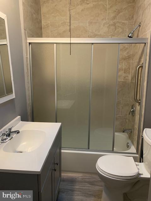 full bathroom featuring vanity, toilet, and enclosed tub / shower combo