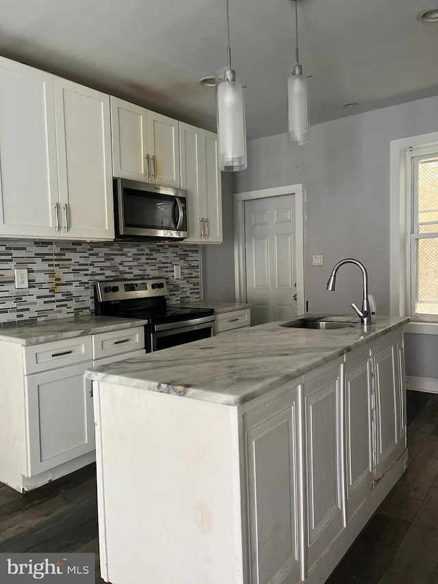 kitchen with white cabinets, appliances with stainless steel finishes, a center island with sink, and sink